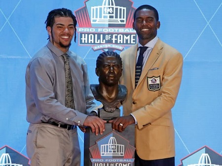 Former NFL wide receiver Randy Moss (right) poses with a bust of himself and with his presenter, son Thaddeus Moss during the inductions at the Pro Football Hall of Fame in August 2018 in Canton, Ohio.