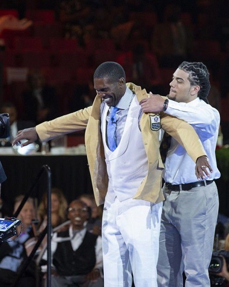 Randy Moss receives his Pro Football Hall of Fame gold jacket from his son and LSU tight-end Thaddeus Moss during the Hall of Fame Gold Jacket dinner on August 3, 2018.