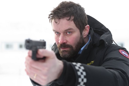 Björn Hlynur Haraldsson in the movie 'Fortitude' pointing a gun at someone.