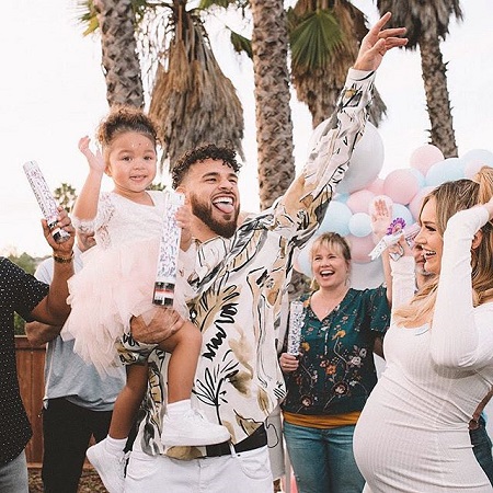 Cory Wharton holding daughter Ryder K with pregnant Taylor Selfridge at their Baby's Gender Reveal Party.