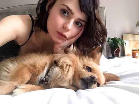 Alexandra Krosney with her dog looking bored in bed.