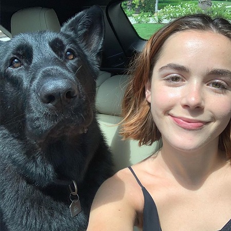 Kiernan Shipka taking a selfie with a black dog.