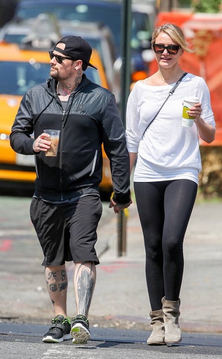 Cameron Diaz and husband Benjamin Madden walking hand in hand with juices in their other hands.