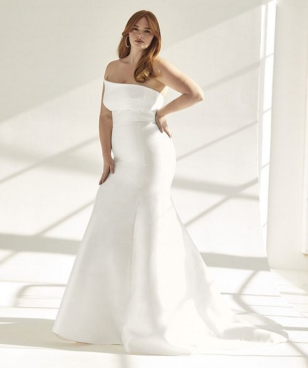 A red-headed model posing in a white wedding dress.