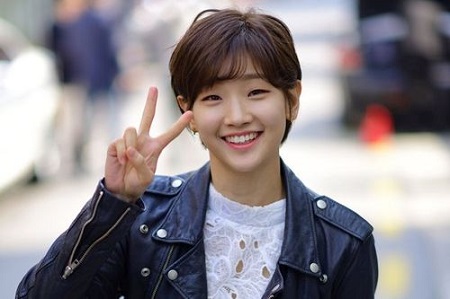 Park So-dam in her short hair with a smile on her face and a peace sign with her right hand.