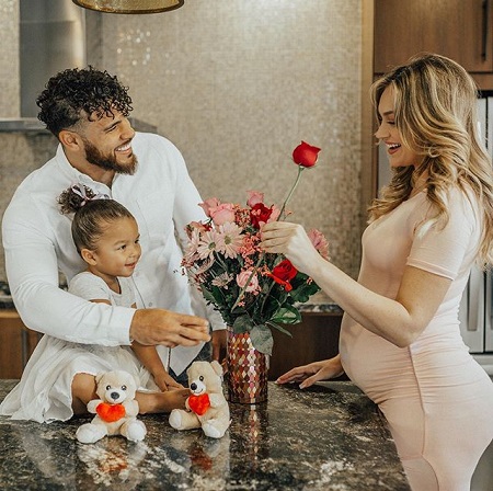 Cory Wharton handing out a rose to pregnant Taylor Selfridge while Ryder K sits on the table, all smiling at each other.