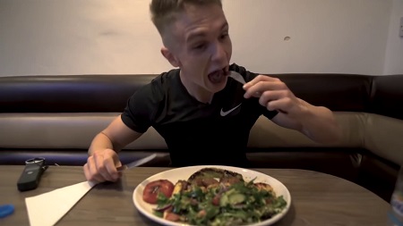 Joe Weller eating from a plate with a fork.