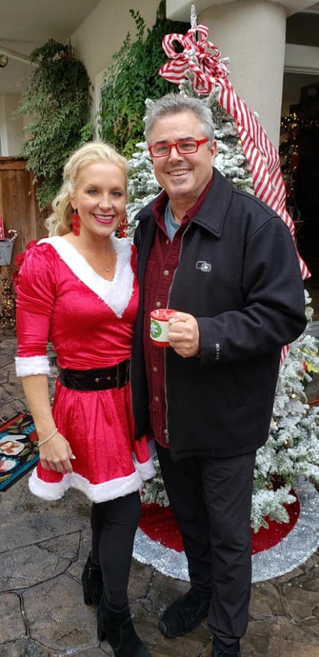 Christopher Knight and his current wife Cara Kokenes in Christmas-themed costume and a Christmas tree behind them.