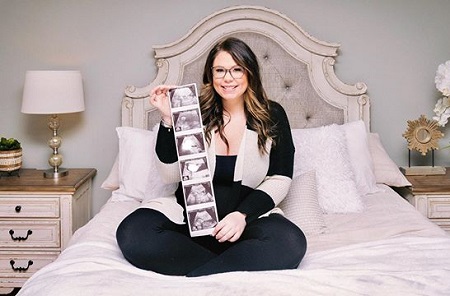 Kailyn Lowry showing a series of ultrasound pictures of her fourth baby while sitting on a bed.