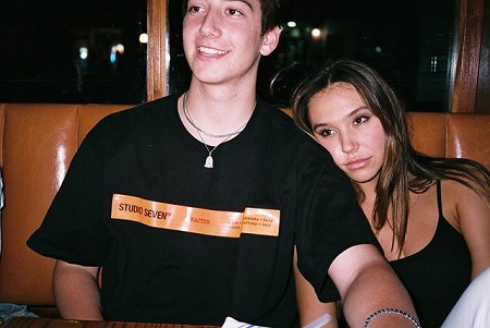 Alexis Ren leaning on to Milo Manheim's shoulder at a dinner.