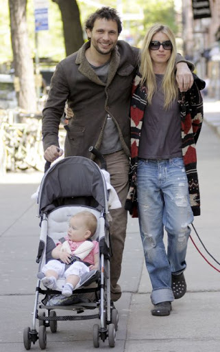 Jeremy Sisto with his arm around wife Addie Lane as he pushes the stroller carrying their daughter with his other hand.