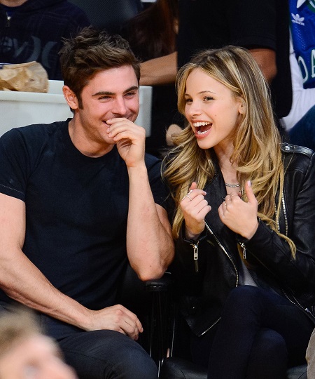 Zac Efron and Halston Sage laugh up as they attend a basketball match in April 2014.