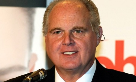 Rush Limbaugh in a position to be about to give a speech in front of a mic.