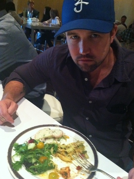 Rob McElhenney in a dinner table eating salad.