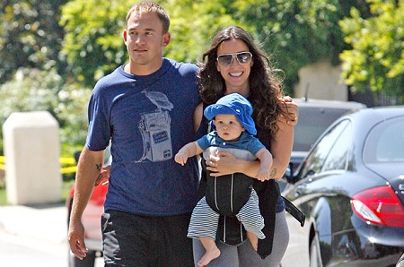 Alanis Morissette with her husband Souleye carrying their son in a baby carrier.