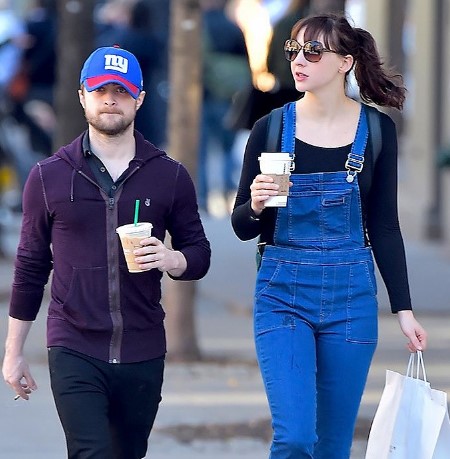 erin darke daniel radcliffe walking on the street with shopping bags on their hands.