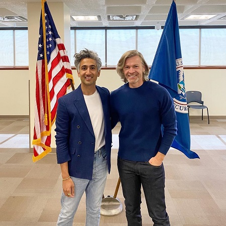 Tan France and his husband Rob in front of the American flag.