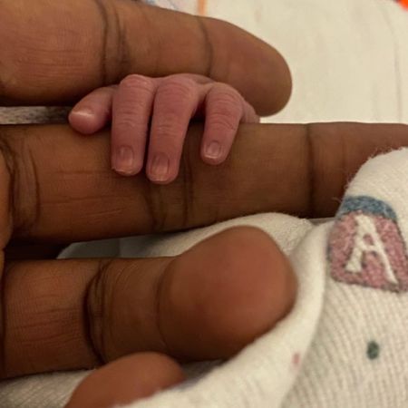 Usher holding the hand of his newborn child
