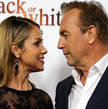Kevin Costner gives stunning wife Christine the look of love as his daughter stuns in daring red gown.