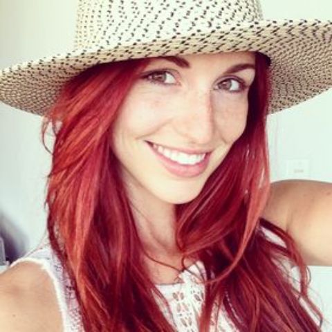 Jacqueline Lowndes with red hair and wearing a hat in the picture.